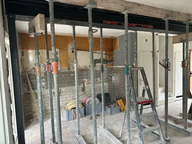 Draagmuur verwijderd in Tilburg 3 Open ruimte na het verwijderen van een draagmuur, met zichtbare stalen balken en houten stutten ter ondersteuning van het plafond in Tilburg